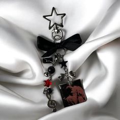 a black and red charm on a white satin background with a star hanging from it's side