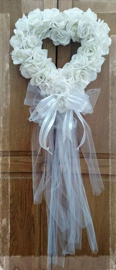 a white wreath with sheer ribbon hanging on a door