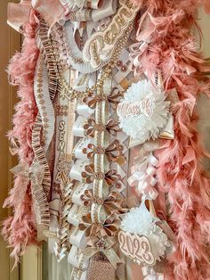 a pink and white dress with feathers on it's chest, hanging in front of a door