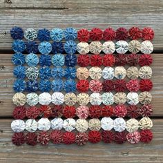 an american flag made out of old red, white and blue paper flowers on a wooden surface