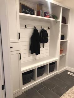 an entryway with white cabinets and storage bins on the wall next to it