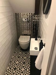 a white toilet sitting in a bathroom next to a black and white tiled counter top