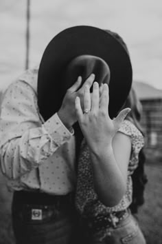 a man in a cowboy hat holding his hand up to his face while standing next to a woman