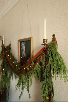 christmas garland hanging on the wall next to a candle holder with a portrait in it