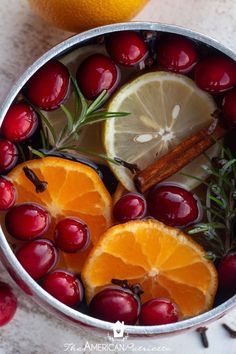 oranges, cranberries and rosemary are in a silver bowl