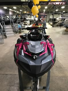 a pink and gray jet ski parked in a garage with balloons hanging from the ceiling