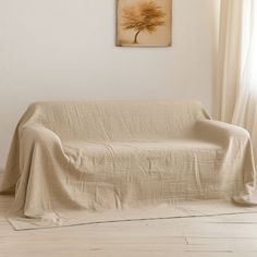 a living room with a couch covered in a beige blanket and a painting on the wall