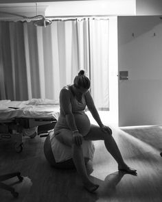 a pregnant woman sitting on the floor in a hospital room with an iv machine nearby