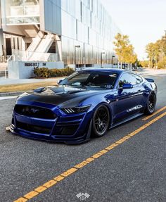 a blue sports car parked on the side of the road in front of a building