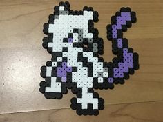 the pixel art is made with black, white and purple beads on a wooden surface