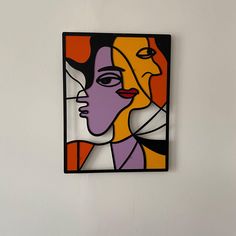 a painting hanging on the wall next to a vase with an orange and purple flower in it