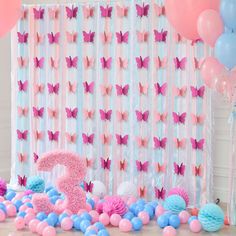 a pink and blue birthday party with balloons, decorations and streamers on the wall