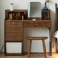 a wooden desk with a mirror, stool and other items on top of it in a bedroom