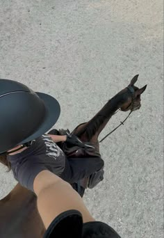 a person riding on the back of a horse wearing a hat and holding it's bridle