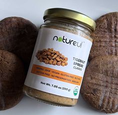 a jar of peanut butter next to two cookies on a white surface with the label nutreu