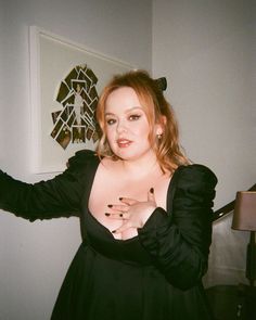 a woman in a black dress posing for the camera with her hands on her hips