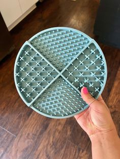 a person holding up a waffle cake pan on a wooden floor in the kitchen