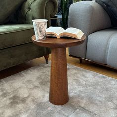 an open book on a table in front of a couch with a cup of coffee