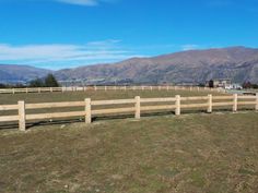 a fenced in field with mountains in the background