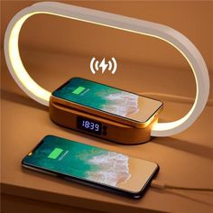 an image of two cell phones charging on a table with the alarm clock lit up