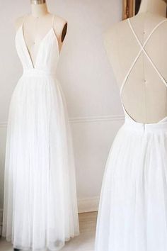 two white dresses on mannequins in front of a mirror and vase with flowers