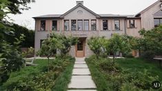 a large house with lots of windows and trees in the front yard, surrounded by greenery