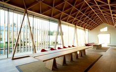 a long wooden table sitting in the middle of a room next to a glass wall