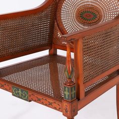 a wooden chair with wicker back and arm rests against a white background, the seat has an intricately carved design on it