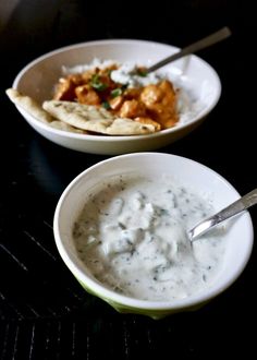 two white bowls filled with food on top of a black table next to each other