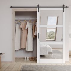 an open closet with clothes hanging on hangers and a bed in the corner next to it