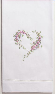 a white towel with pink and green flowers in the shape of a heart on it