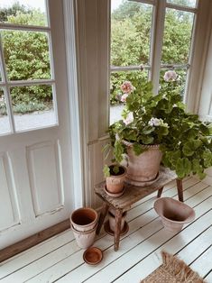 some potted plants sitting on a wooden bench in front of a door and window