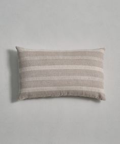 a beige and white striped pillow sitting on top of a gray wall