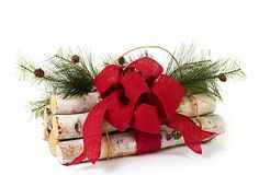 a red bow is tied on top of birch logs with pine cones and evergreen branches