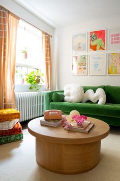 a living room with green couches and pictures on the wall above it's coffee table