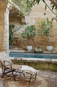 a patio with chairs and potted plants next to a pool in the middle of it