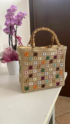 a purse sitting on top of a table next to a vase with flowers in it