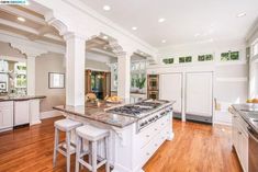 a large kitchen with an island and two stools next to it on a hard wood floor