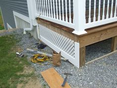 a wooden bench sitting on top of a gravel covered ground next to a white fence