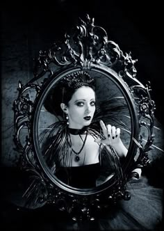 a woman is holding her hand up in front of a mirror with an ornate frame