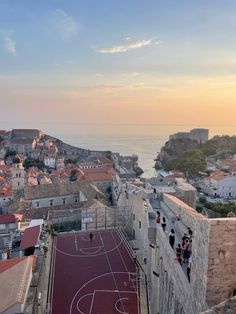 an aerial view of a basketball court in the city with people standing on it and looking out at the water