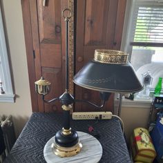 a lamp on top of a table with a black shade and gold trim around it