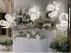 a room filled with lots of white flowers and potted plants on top of each other