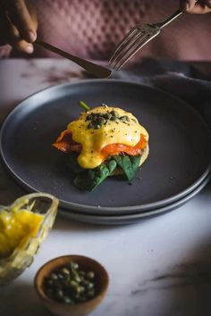 a person is eating an omelet on a plate with a fork and knife