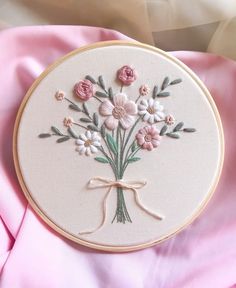 a close up of a embroidery on a pink cloth with flowers in it and a bow