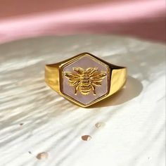 A Unique And Beautiful Ring, Showcasing Pearlized Enamel And 18k Yellow Gold Over Stainless Steel. This Ring's Honeycomb Shape Is Unique, And It Exudes "Gucci Vibes". A Great Piece To Add To Your Collection! Brand New Never Used Without Tags 18k Yellow Gold Over Stainless Steel Pearlized Enamel & Golden Bee Detail *Love It, But It's Not Your Size? Let Me Know In The Comments And I'll Be Happy To Order It For You! Honeycomb Shape, Jewelry Lookbook, Enamel Ring, Gold Enamel, Enamel Jewelry, Beautiful Ring, Womens Jewelry Rings, Honeycomb, Be Happy