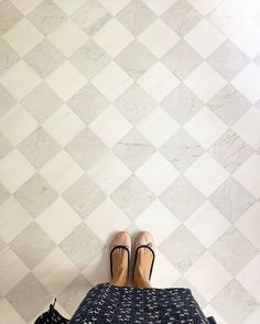 a woman's legs and shoes on top of a bed in front of a tiled wall