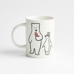 a white coffee mug with an image of two penguins and a bear