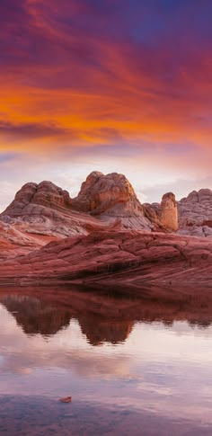 the mountains are reflected in the still water at sunset, with pink and orange clouds