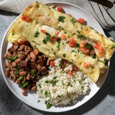 a white plate topped with rice, beans and an omelet